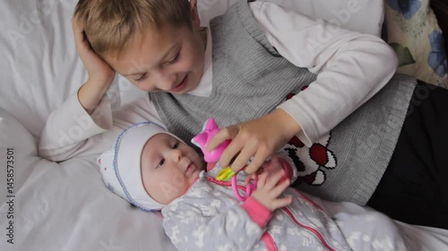 brother plays with baby, older brother takes care of little sister, two children play on bed