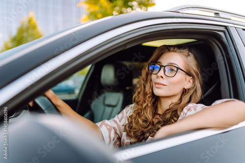 Wallpaper Mural Beautiful woman driving a car, enjoying the ride. Young female driver in glasses at sunset. Transport and leisure concept. Torontodigital.ca