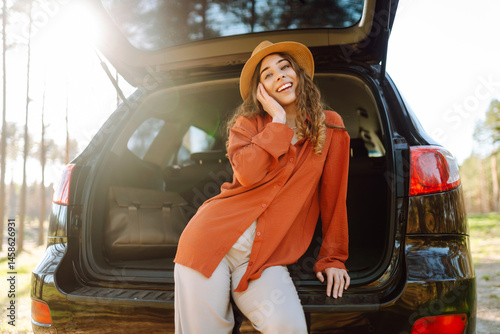 Wallpaper Mural Joyful woman sits in the trunk of a car at sunset in the forest. Traveler enjoys nature, feels freedom. Road trip, weekend concept. Active lifestyle. Torontodigital.ca
