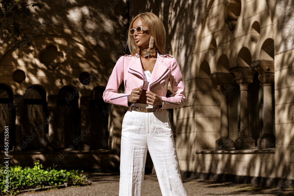 Beautiful and elegant woman in classic white fashionable suit sensually walks around the city on a sunny summer day. Elegance. Businesswoman look.