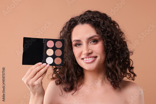 Bild auf Leinwand Smiling woman with eyeshadow palette on beige background