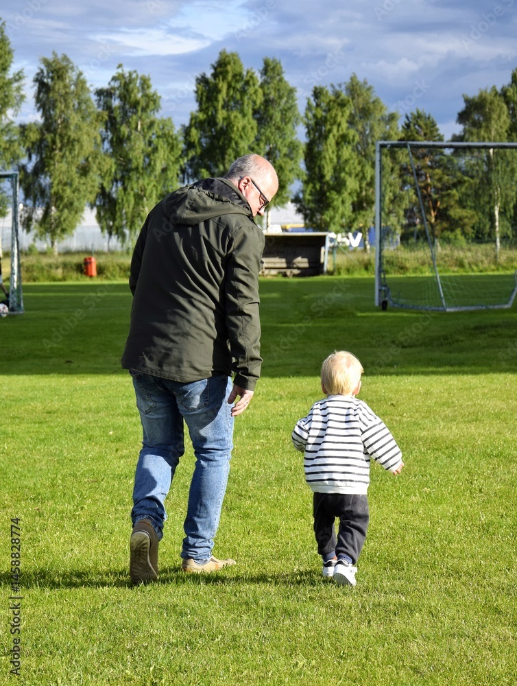 Obraz premium Grandfather and his little grandson run together, play. Children's Day, Family Day.