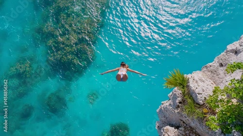 Adventurous Woman Diving into Crystal Clear Ocean Waters from Cliff