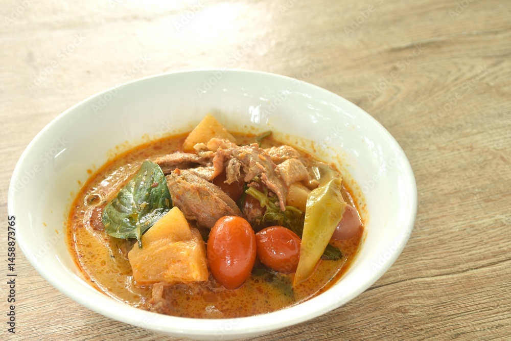 spicy boiled roasted duck meat with pineapple and tomato in coconut milk curry soup on bowl
