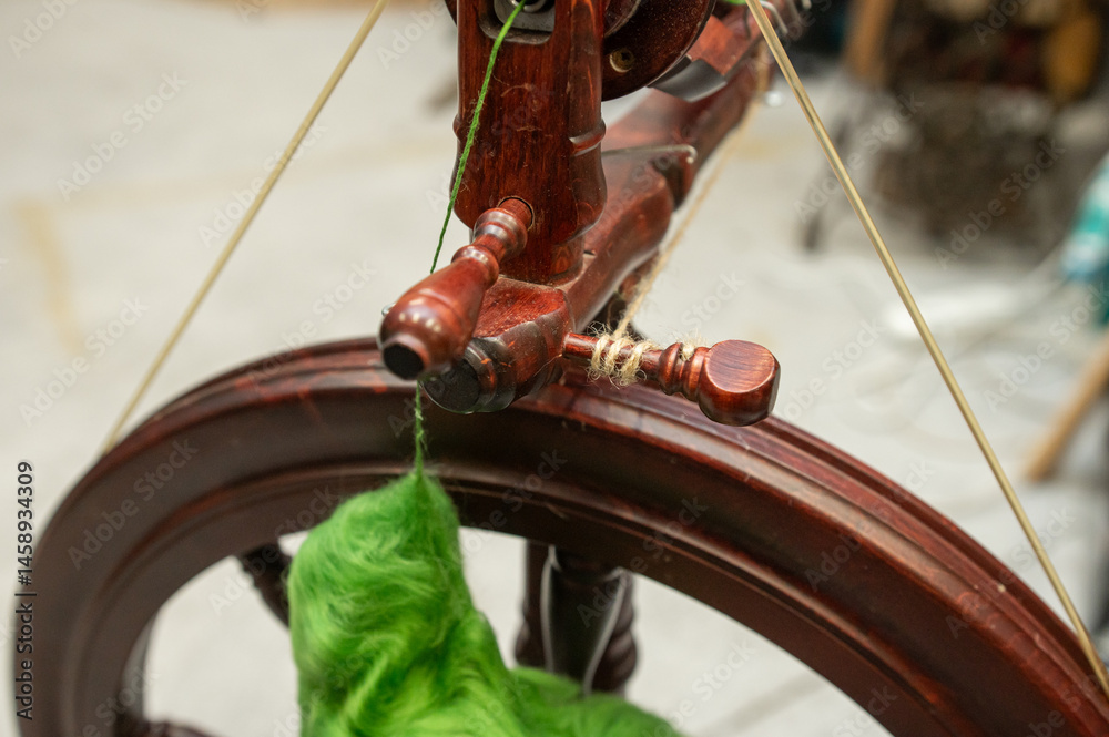 Distaff Day Close-up of vintage spinning wheel with green wool yarn