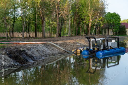 Dredging operation in a pond or lake, with equipment and tubing visible for environmental cleanup project.