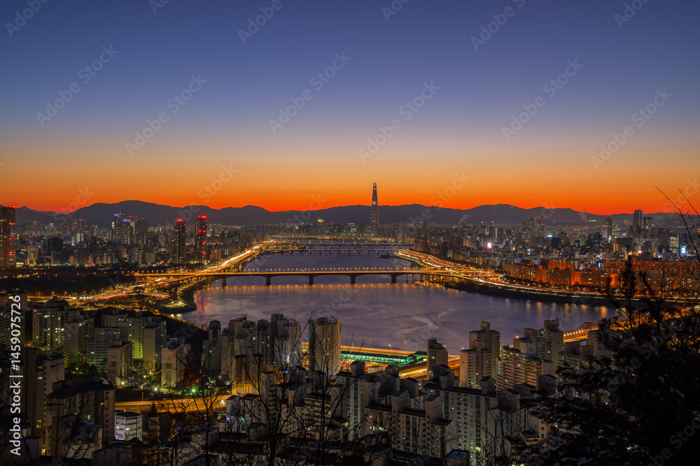 Obraz premium SEOUL, The golden light before sunrise offers a beautiful view of the Han River and Lotte World Tower on Maebongsan Mountain in Seoul, South Korea.