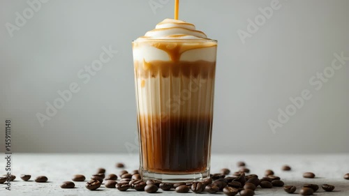 Chilled latte served in a glass with beans in the backdrop