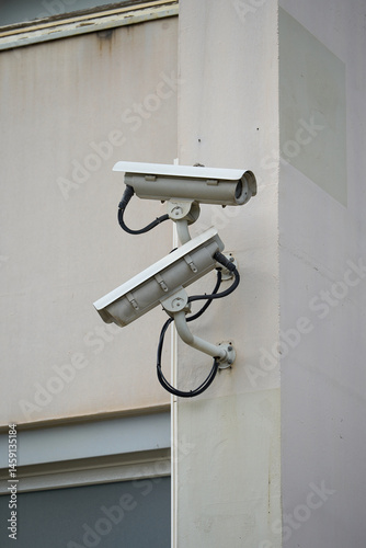 Two outdoor surveillance cameras on the wall, security system. Surveillance cameras are installed at the industrial site to secure the area.