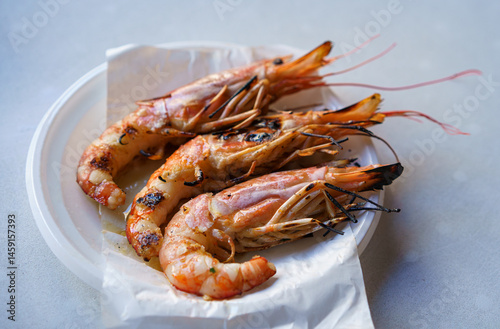 Grilled shrimp served on a white plate on the table.