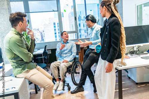 Obraz na płótnie Diverse business team discussing in modern office with disabled colleague in wheelchair w salonie