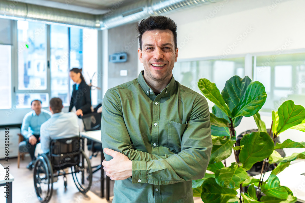 Confident businessman smiling with arms crossed in accessible office environment