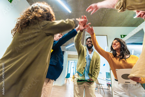Business team celebrating success joining hands in modern office