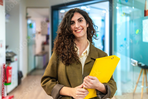 Obraz na płótnie Smiling businesswoman holding a yellow folder in the office w salonie