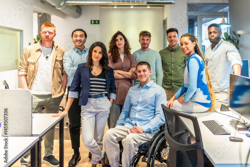 Diverse business team posing together in modern office with disabled colleague