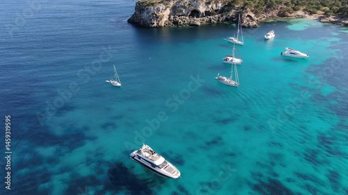 Static view of several luxury yachts  anchored in a cove in the coast of Mallorca. 