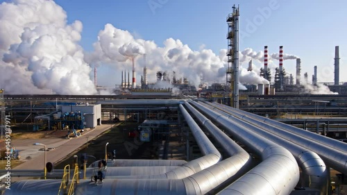 Industrial complex with pipes and smoke billowing into the sky