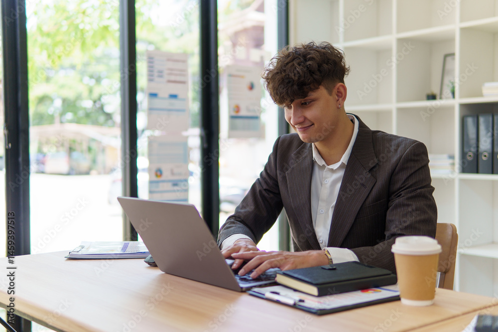 Young office worker concentrates on his laptop, working in a contemporary workspace. Young office worker concentrates on his laptop, working in a contemporary workspace.
