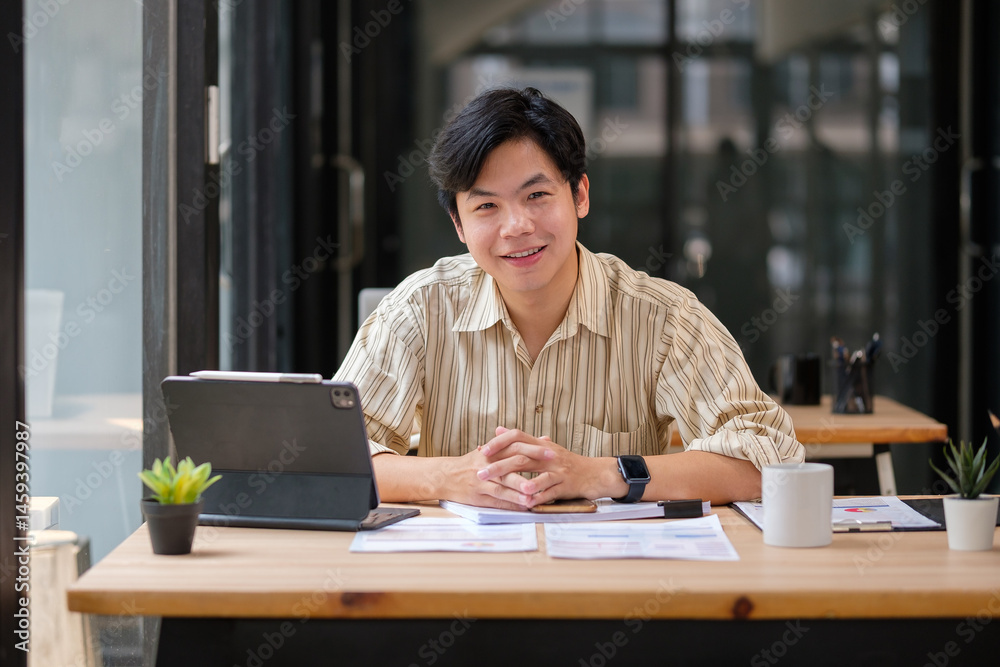 Portrait of a handsome male office worker sitting at his workspace. Portrait of a handsome male office worker sitting at his workspace.