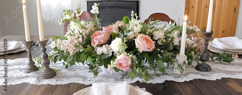 A table with a lace table runner and a floral centerpiece