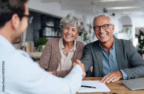 A cheerful elderly couple seals a deal with a consultant via a friendly handshake.
