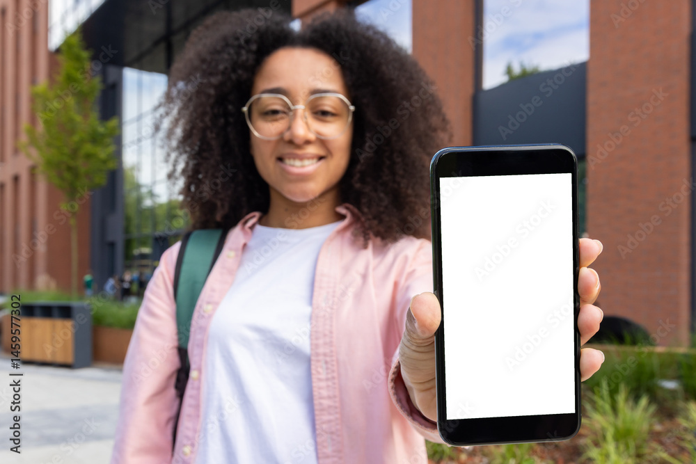 A smiling young woman holds up her smartphone with a blank screen, perfect for mockups or app displays outdoors.