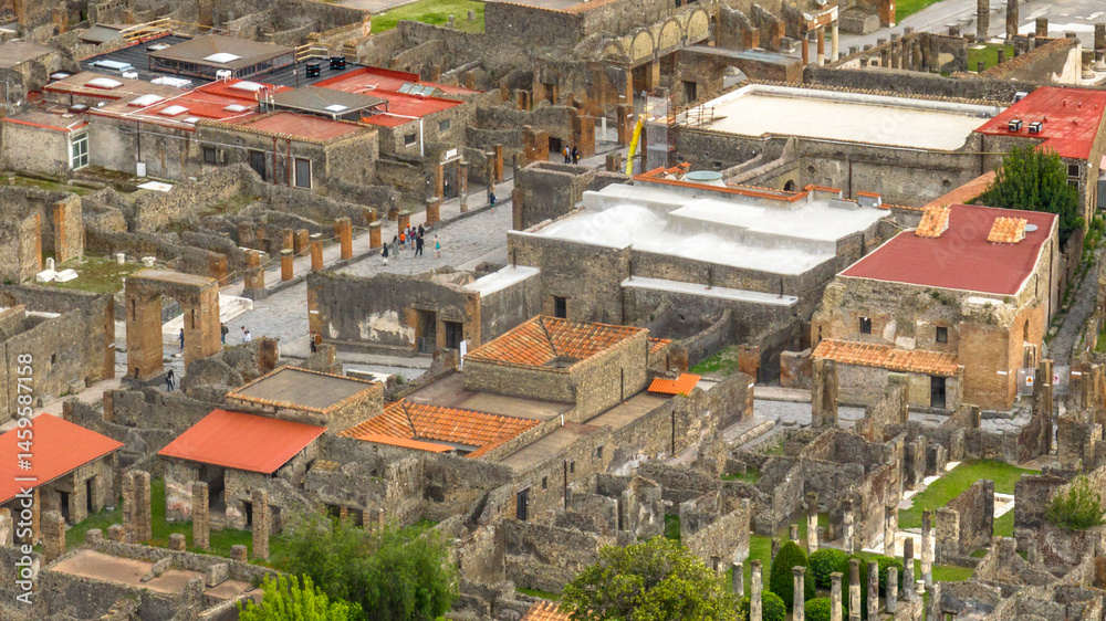 Fototapeta premium Aerial view of the ruins of houses and buildings of the ancient Roman city of Pompeii. The archaeological park is located in the province of Naples, Campania, Italy.