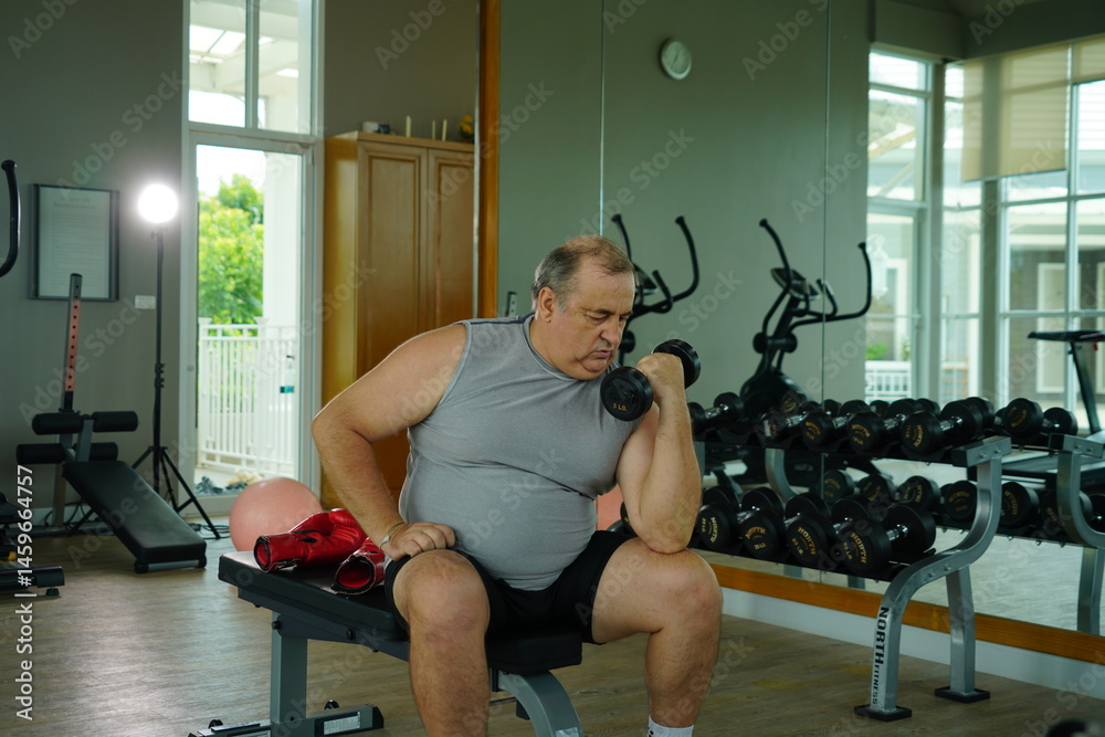 Elderly Caucasian man with a fat belly wearing gym clothes lifting dumbbells doing exercises to build muscle for health and lose weight in a fitness center Health and wellness concept