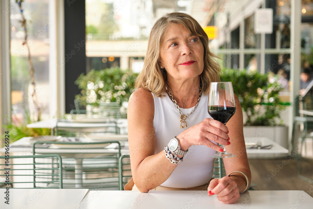 Elegant businesswoman enjoying a glass of red wine while relaxing at an outdoor restaurant