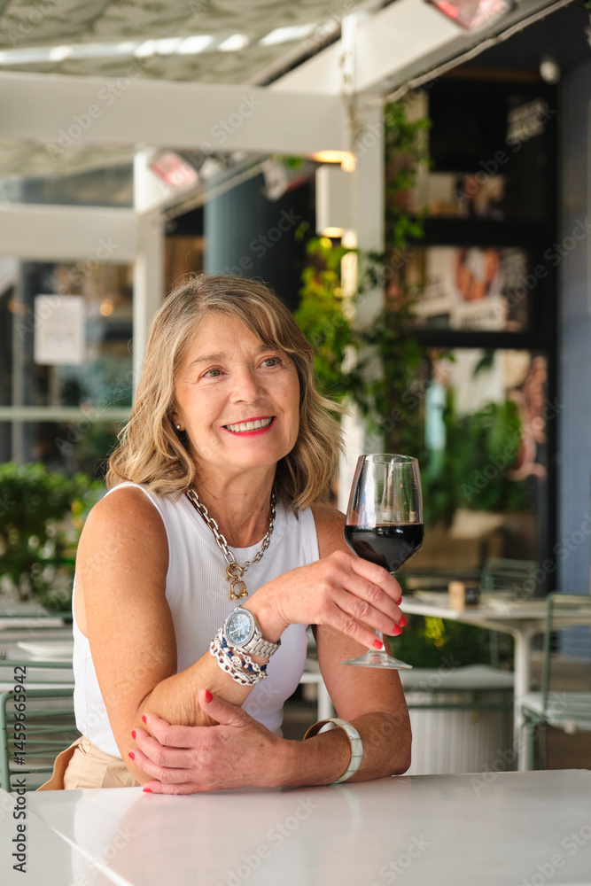 Smiling mature woman drinking red wine at a restaurant's terrace