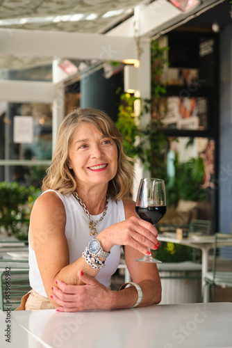 Obraz na płótnie Smiling mature woman drinking red wine at a restaurant's terrace w salonie