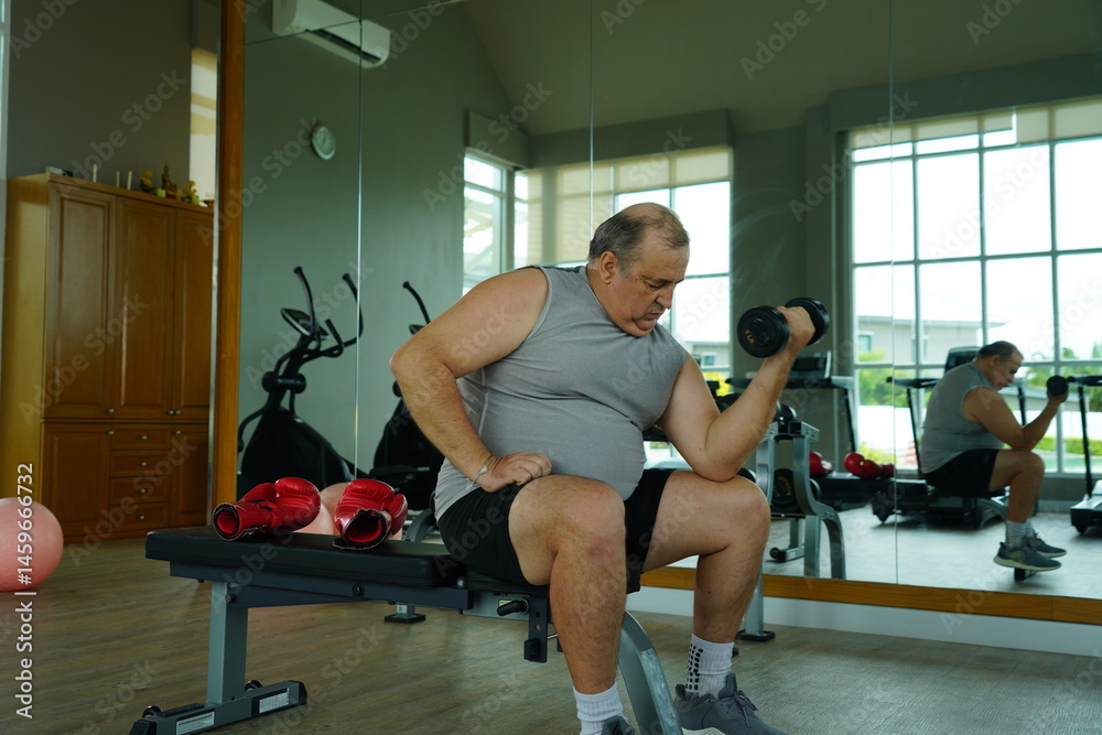 Elderly Caucasian man with a fat belly wearing gym clothes lifting dumbbells doing exercises to build muscle for health and lose weight in a fitness center Health and wellness concept