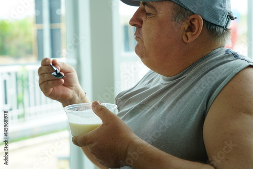 Obraz na płótnie Fat Caucasian senior man with potbelly after workout hungry eating breakfast yoghurt,fruit salad healthy food and weight loss in fitness club. Health and wellness concept. w salonie