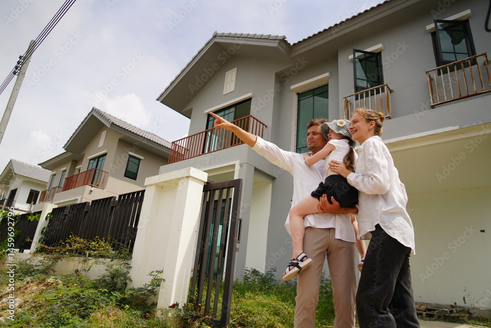 Caucasian family father holding seven year old daughter with mother standing together buying a new house in a housing project planning finance insurance home loan to build a family in the future