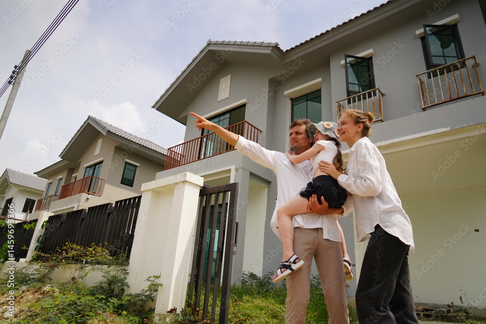Caucasian family father holding seven year old daughter with mother standing together buying a new house in a housing project planning finance insurance home loan to build a family in the future