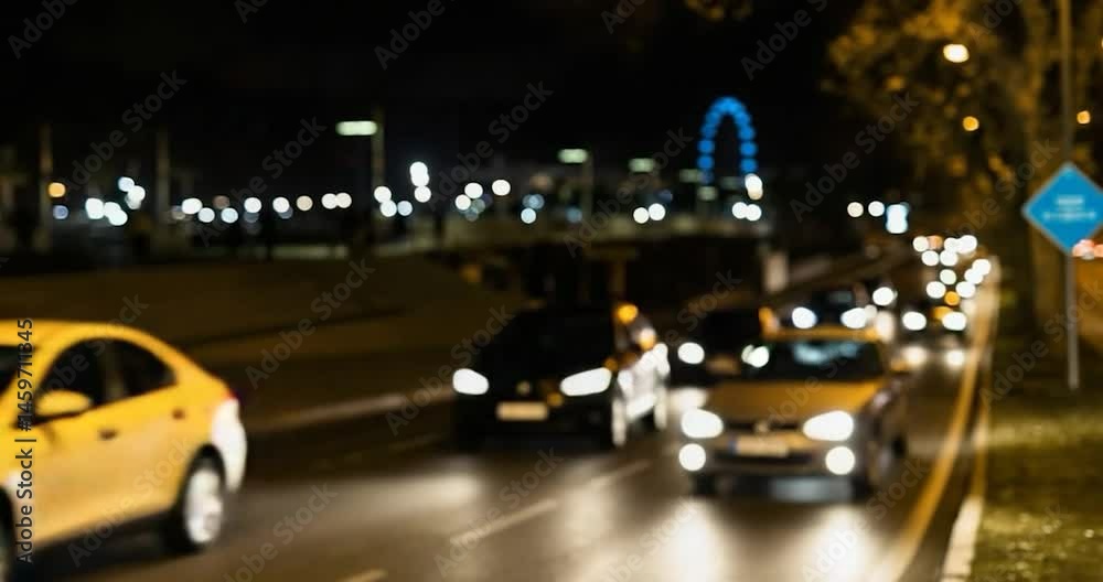 Cars with headlights on driving on a city road at night with bokeh lights.