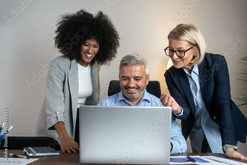 Three busy happy middle aged professional business man and two women executive leaders team using laptop working on computer at work desk having conversation on financial project at meeting in office.