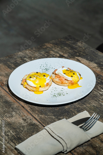 Egg benedict or poached egg with salmon on white plate. Isolated by wooden background or table. Food photography