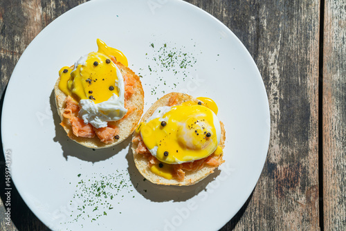 Egg benedict or poached egg with salmon on white plate. Isolated by wooden background or table. Food photography