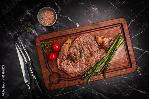 Obraz na płótnie Beef grill steak with green asparagus on a cutting board. Healthy dinner or lunch, top view. High quality photo w salonie