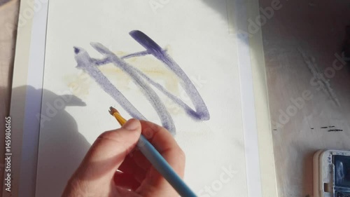 Female hand drawing abstract patterns with watercolor on white paper in artistic process sequence.
