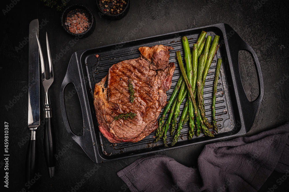 Beef grill steak with green asparagus on a grill pan. Healthy dinner or lunch, top view. High quality photo