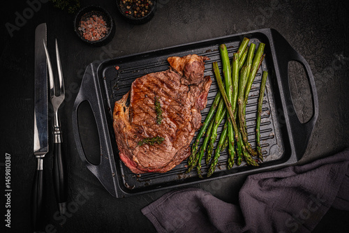 Obraz na płótnie Beef grill steak with green asparagus on a grill pan. Healthy dinner or lunch, top view. High quality photo w salonie