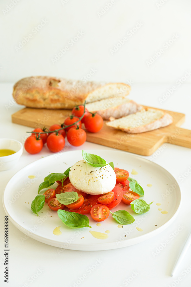 Salad Caprese with tomato, cherry, mozzarella and basil leaves on white wooden table Salad Caprese with tomato, cherry, mozzarella and basil leaves on white wooden table