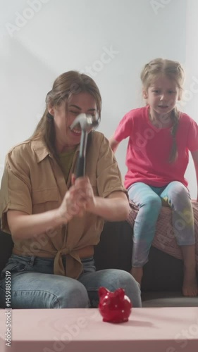 young mother with children breaks piggy bank with hammer with money in form of pig, money box doit