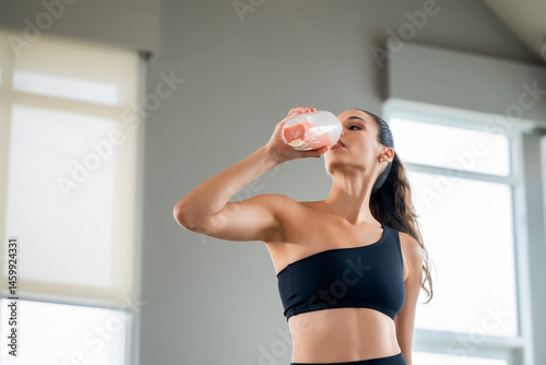 Confident woman in fitness attire drinks a healthy protein smoothie after a workout, embodying strength, freshness, and a modern active lifestyle.