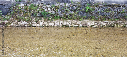 Obraz na płótnie The shallow, clear water of the Gradna River flows gently along a moss-covered stone embankment in Samobor w salonie