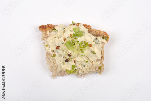 Obraz na płótnie A piece of bread topped with vegan cheese spread and sprouts is isolated on a white surface w salonie