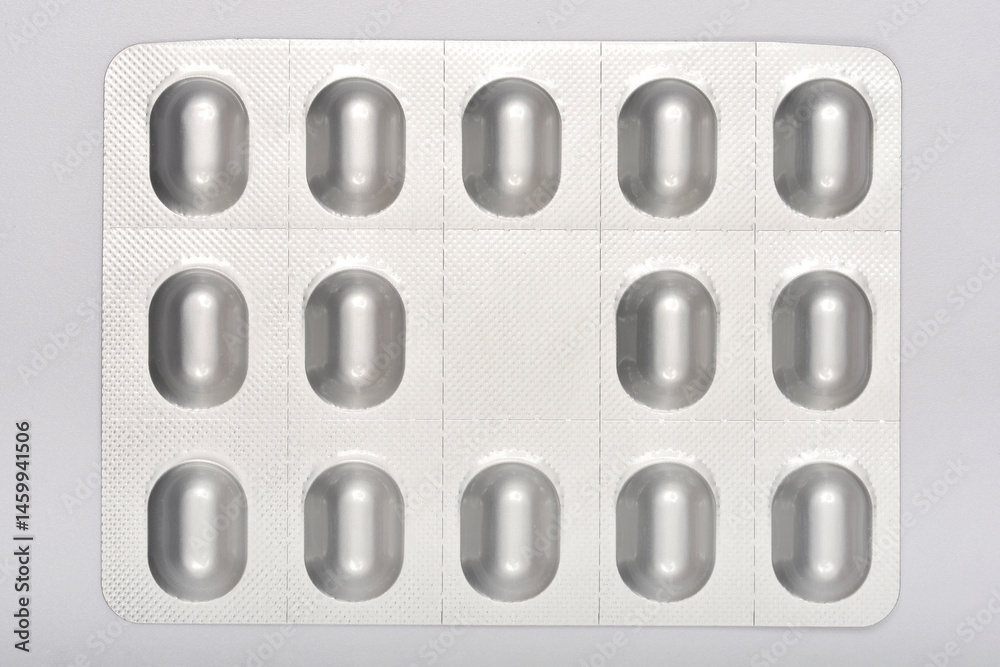 Silver blister pack of oval pills against a neutral background, suggesting medication, healthcare, and pharmaceuticals