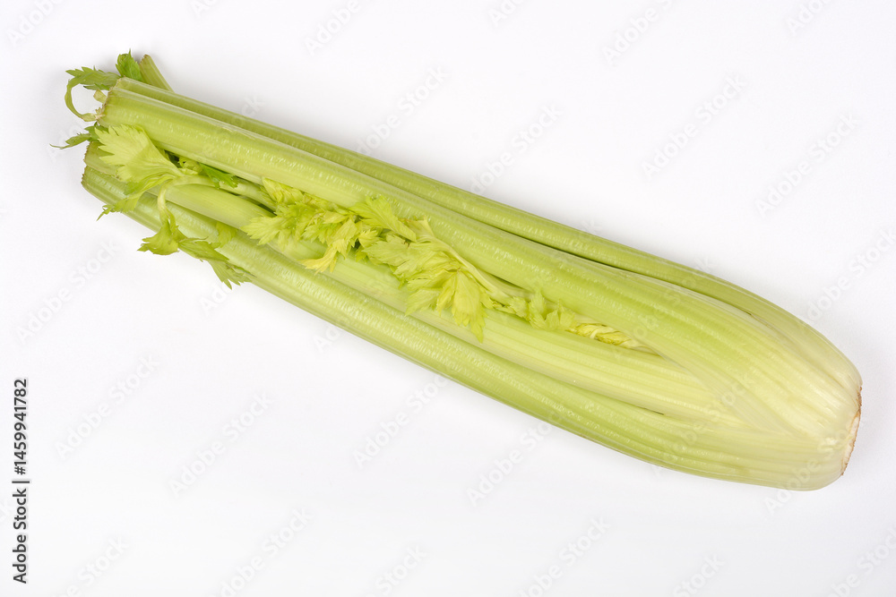 A bunch of fresh, light green celery stalks with leaves is shown diagonally on a plain white background